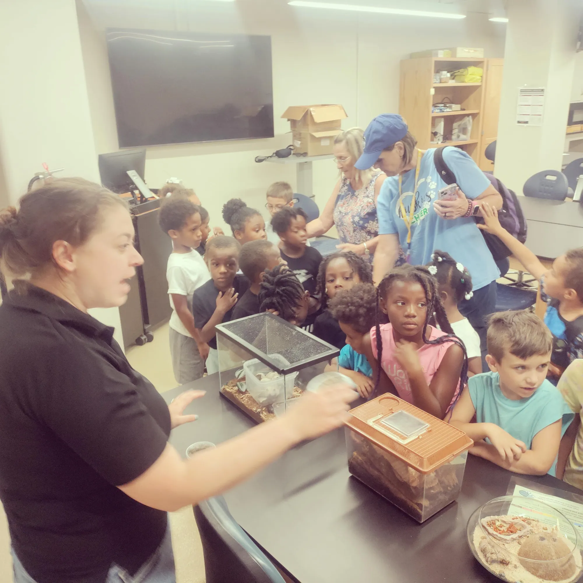 Youth participants gathered around a science learning demonstration with instructors